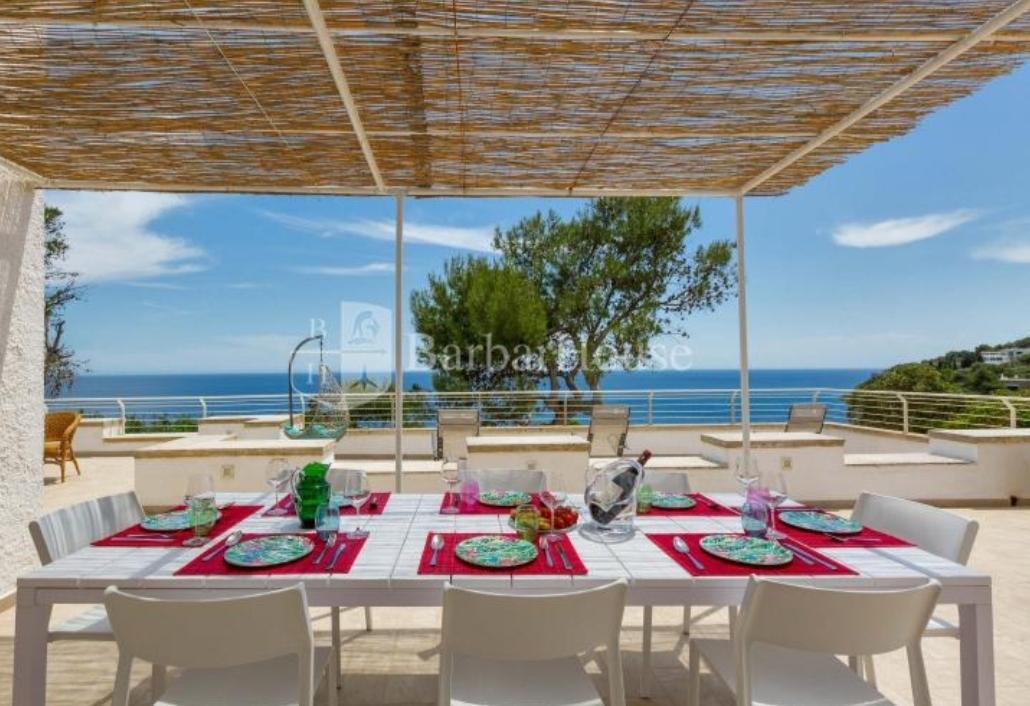 Gedekte tafel op een overdekt terras met uitzicht op zee